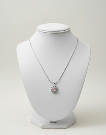 Silver pendant necklace with a pink floral crystal stone on a white display stand.